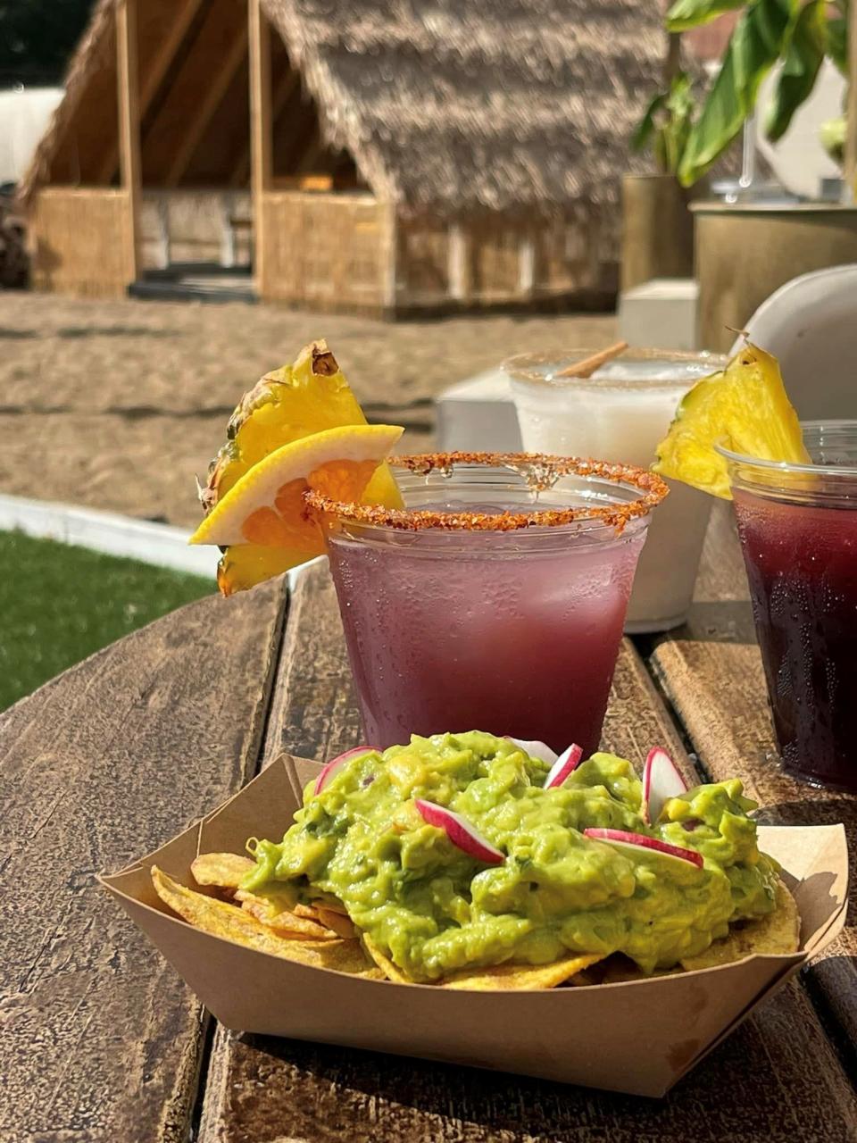 Guacamole is served with radish slices and plantain chips alongside cups of horchata, sangria, and hibiscus agua fresca at NOCO Park's summer installation, NOCO Villa.