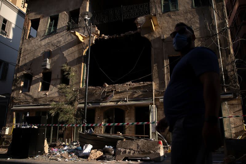 Un hombre con mascarilla camina frente a una casa tradicional libanesa dañada luego de una enorme explosión en el área del puerto de Beirut