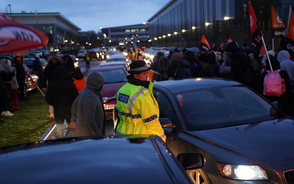 A police officer monitors Amazon staff members on a GMB union picket line