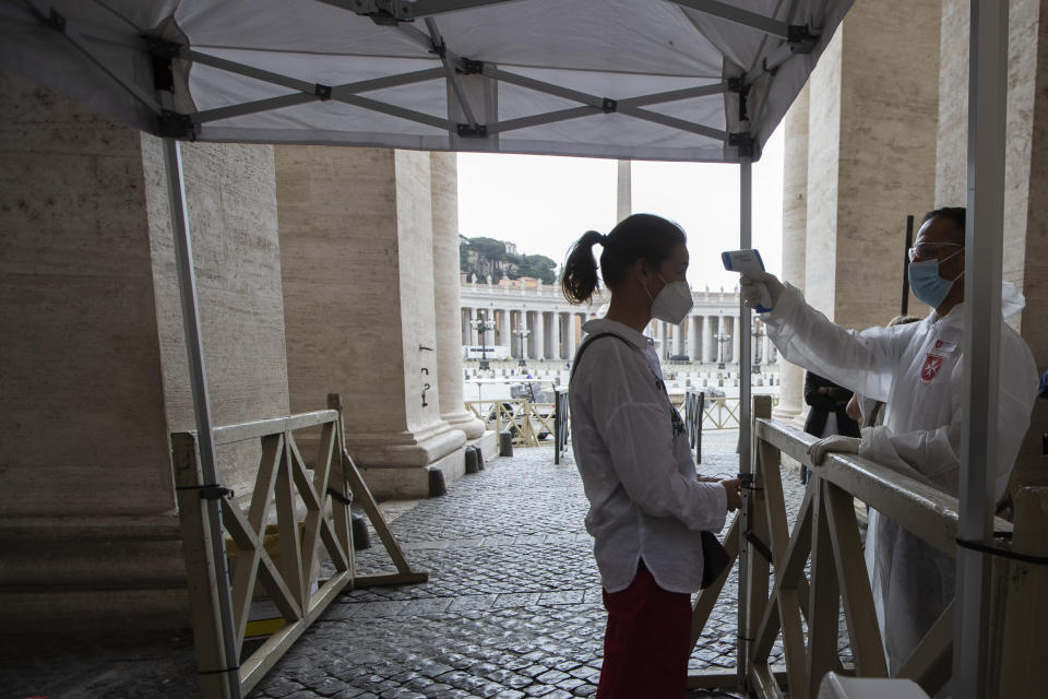 A visitor has her temperature checked in St. Peter's square at the Vatican in the day of the reopening of the Basilica, Monday, May 18, 2020. Italy is slowly lifting sanitary restrictions after a two-month coronavirus lockdown. (AP Photo/Alessandra Tarantino)