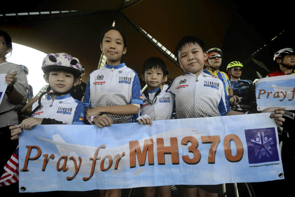 Cyclists hold a banner reading "Pray for MH370" during "The Ride of Prayer" for the missing Malaysia Airlines, flight MH370, outside the departure hall of Kuala Lumpur International Airport in Sepang, Malaysia, Sunday, March 23, 2014. Search planes headed back out to a desolate patch of the southern Indian Ocean on Sunday in hopes of finding answers to the fate of the missing Malaysia Airlines jet, after China released a satellite image showing a large object floating in the search zone. (AP Photo/Joshua Paul)