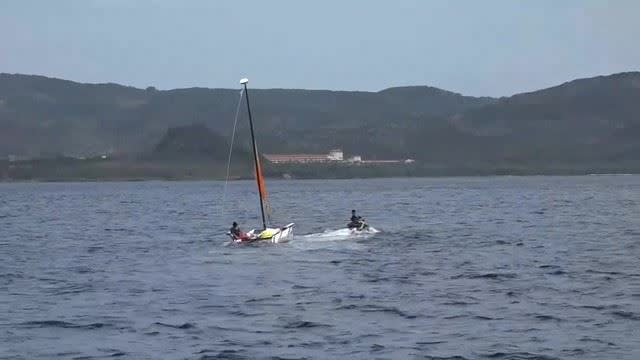 船長在帆船上，由水上摩托車業者拖帶返回小灣沙灘。（圖／海巡署南部分署提供）