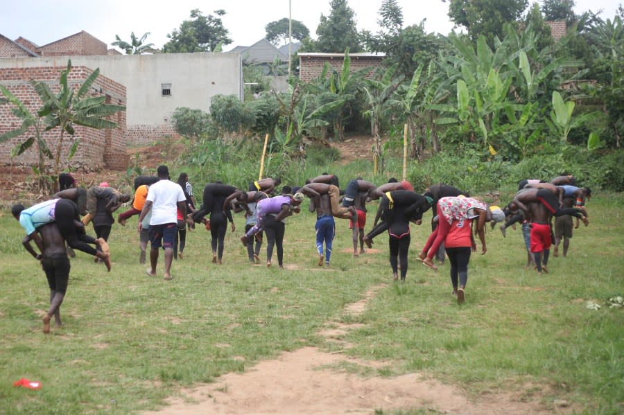 Ugandan youths train before an amateur wrestling tangle in the soft mud in Kampala, Uganda Wednesday, March. 20, 2023. The open-air training sessions, complete with an announcer and a referee, imitate the pro wrestling contests the youth regularly see on television. While a pair tangles inside the ring, made with bamboo poles strung with sisal rope, others standing ringside cheer feints and muscular shows of strength. (AP Photo/Patrick Onen)