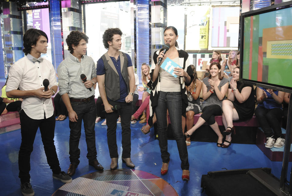 FILE - The Jonas Brothers, from left, Joe, Nick and Kevin, chat with VJ Lyndsey Rodrigues during a co-hosting appearance on MTV's "Total Request Live" on Aug. 11, 2008, in New York. CBS News is rebuilding MTV's old studio as its headquarters for election night. The network is installing giant touchscreens and "augmented reality" displays for the big political night and says it will provide extra roominess to put on a television show in the COVID-19 era. (AP Photo/Evan Agostini, File)
