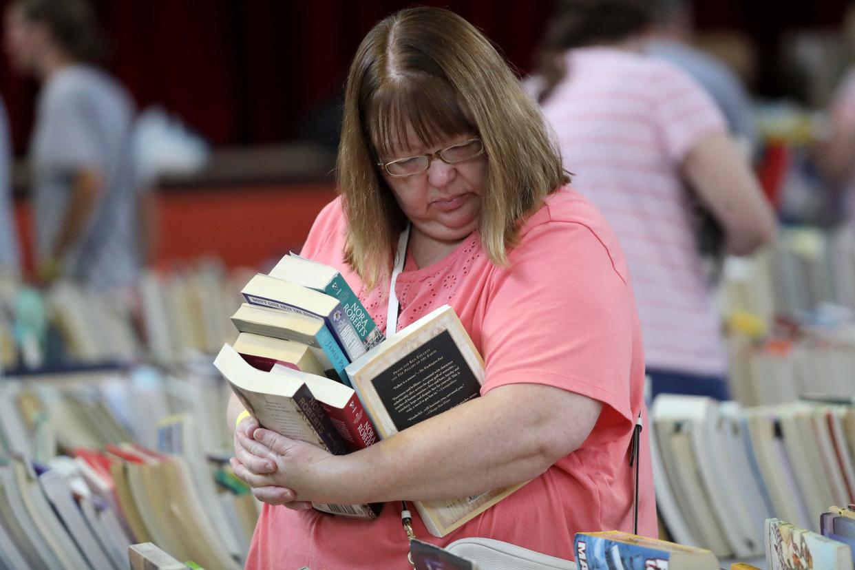 North Georgetown's Shari Oswalt holds an armful of books while shopping for more Saturday, Aug. 5, 2023, in the main auditorium at The Commons on South Linden Avenue during the Friends of Rodman Public Library's annual Used Book Sale.