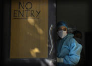 A health worker in personal protective equipment awaits patients for Covid 19 testing at a health center, in New Delhi, India, Friday, Jan. 28, 2022. Indian health officials said that the first signs of COVID-19 infections plateauing in some parts of the vast country were being seen, but cautioned that cases were still surging in some states. (AP Photo/Manish Swarup)