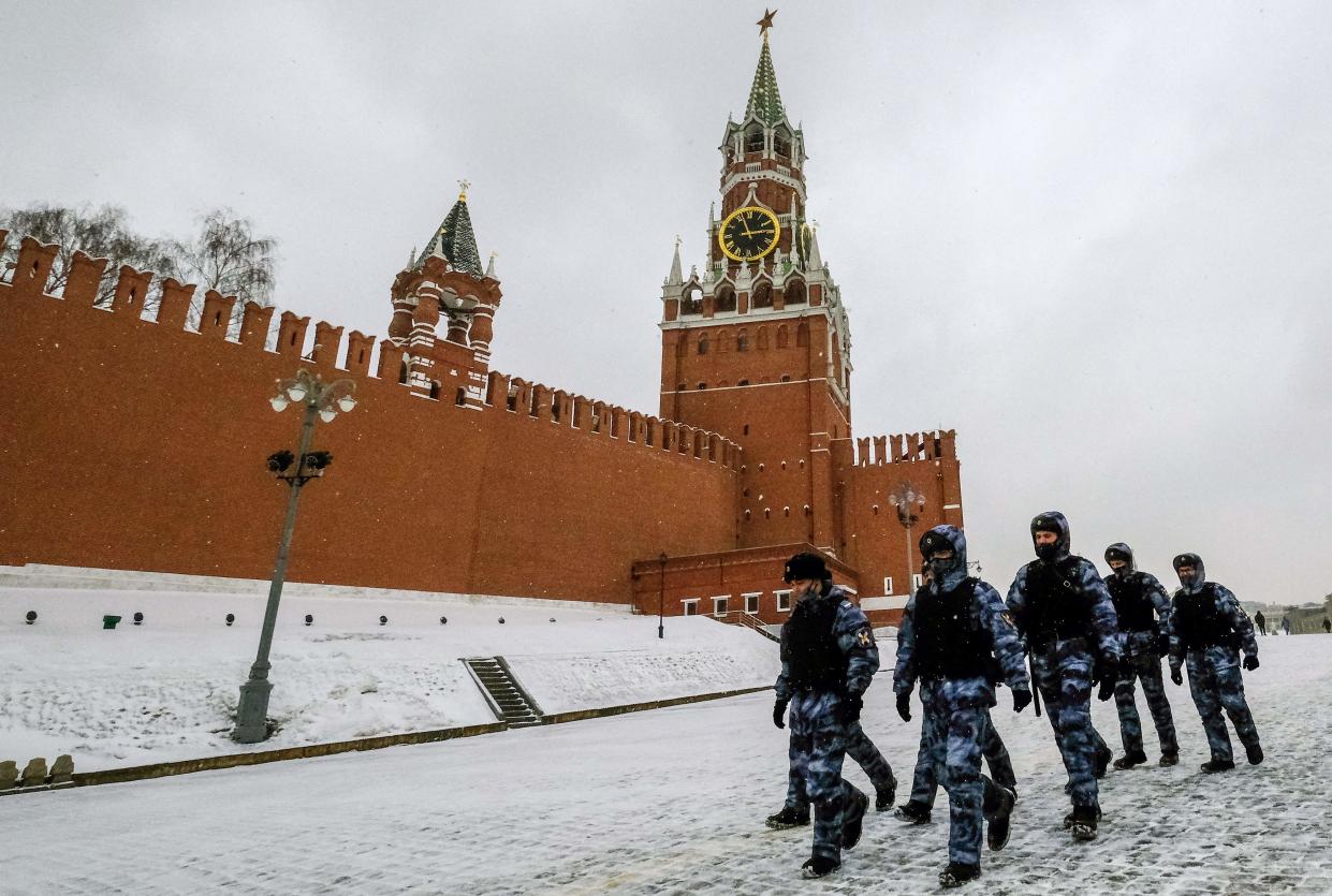 Agentes de policía con máscaras protectoras pasan por la Torre Spasskaya del Kremlin en Moscú el 13 de marzo de 2021 (AFP via Getty Images)
