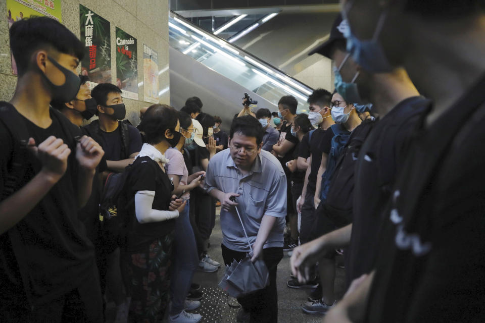 A man squeezes through protesters blocking the lobby of the Hong Kong Revenue Tower in Hong Kong on Monday, June 24, 2019. Hong Kong has been rocked by major protests for the past two weeks over legislative proposals that many view as eroding the territory's judicial independence and, more broadly, as a sign of Chinese government efforts to chip away at the city's freedoms. (AP Photo/Kin Cheung)
