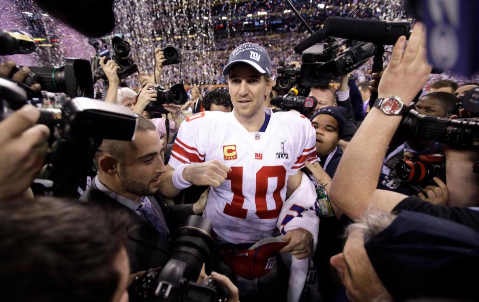 New York Giants quarterback Eli Manning, center, is surrounded by photographers as he celebrates his team's 21-17 win against the New England Patriots after the NFL Super Bowl XLVI football game Sunday, Feb. 5, 2012, in Indianapolis.