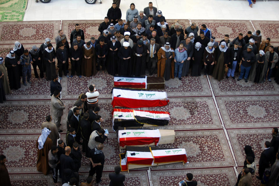 FILE - In this file photo taken Tuesday, Jan. 21, 2014, mourners pray over five coffins draped with Iraqi flags for Iraqi soldiers killed by al-Qaida militants in Anbar province during their funeral procession inside the shrine of Imam Ali in Najaf, 100 miles (160 kilometers) south of Baghdad, Iraq. The Islamic State of Iraq and the Levant has claimed responsibility for the execution-style killings of the four Iraqi commandos near Fallujah, Anbar province. The other soldier was killed during clashes. (AP Photo/Jaber al-Helo, File)