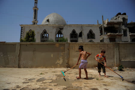 Children clean the floor with mops in the Baba Amr neighbourhood of Homs, Syria July 28, 2017. Picture taken July 28, 2017. REUTERS/Omar Sanadiki