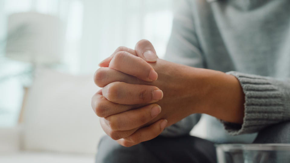 Closeup of young Asian female psychotherapist discussing a problem and touch hand young depressed sit on couch at clinic. Medical insurance, Mental health concept.