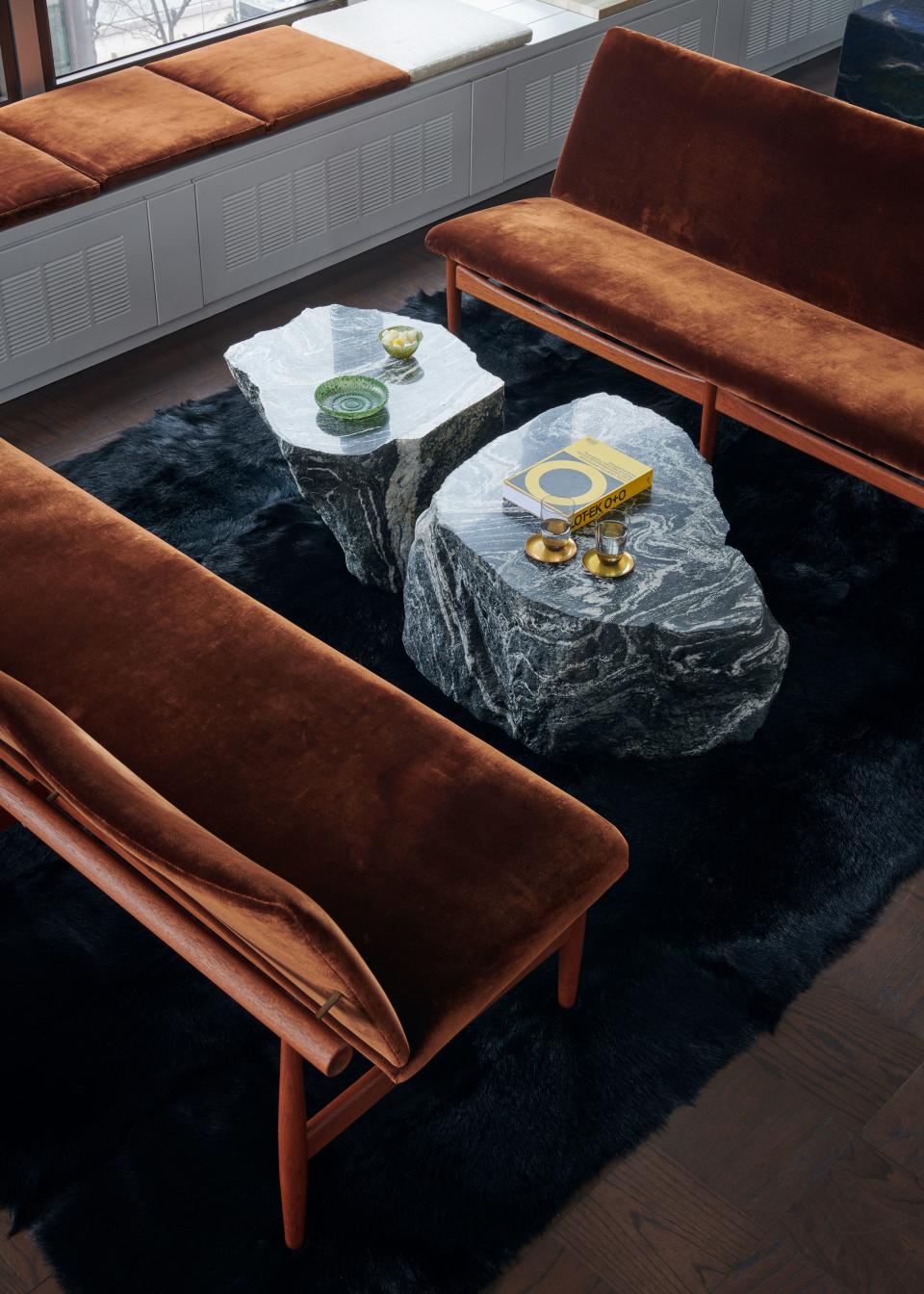 The living room has a pared-down yet bold look. These velvet sofas, designed in 1953 by Finn Juhl, were inspired by traditional Japanese building techniques. The coffee tables are stone sculptures by Korean artist Yongjin Han, and the black goat-hair rug is from Mark Nelson Designs.