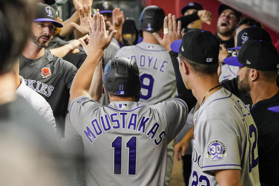 Colorado Rockies' Mike Mustakas (11) and Brenton Doyle (9) are greeted by teammates after they scored against the Arizona Diamondbacks during the second inning of a baseball game Monday, May 29, 2023, in Phoenix. (AP Photo/Darryl Webb)