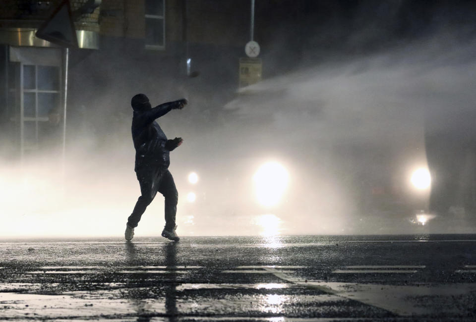 A Nationalist youth confronts police lines near the Peace Wall in West Belfast, Northern Ireland, Thursday, April 8, 2021. Authorities in Northern Ireland sought to restore calm Thursday after Protestant and Catholic youths in Belfast hurled bricks, fireworks and gasoline bombs at police and each other. It was the worst mayhem in a week of street violence in the region, where Britain's exit from the European Union has unsettled an uneasy political balance. (AP Photo/Peter Morrison)