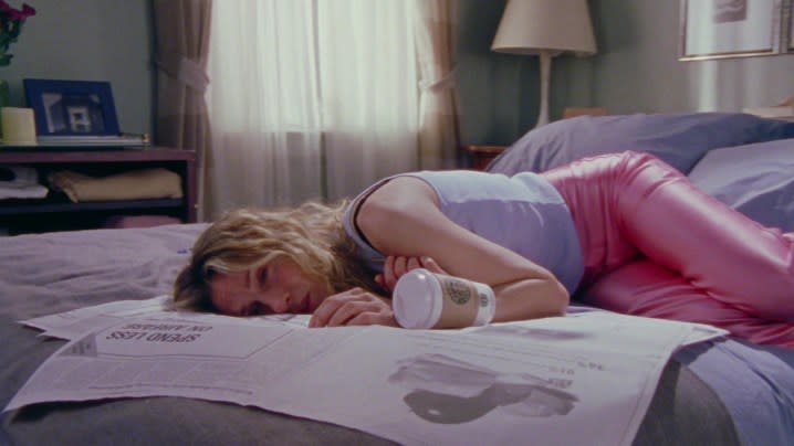 Sarah Jessica Parker as Carrie Bradshaw laying on top of a newspaper in her bed in Sex and the City.