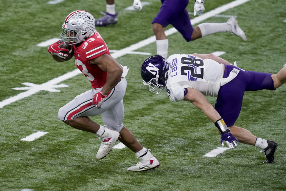 Ohio State running back Master Teague III, left, runs with the ball past Northwestern linebacker Chris Bergin (28) during the first half of the Big Ten championship NCAA college football game, Saturday, Dec. 19, 2020, in Indianapolis. (AP Photo/Darron Cummings)