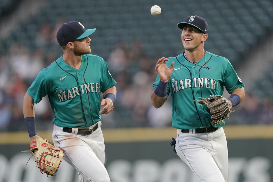 Seattle Mariners first baseman Jake Bauers, left, tosses the ball to second baseman Dylan Moore after Bauers caught a pop-up hit by Tampa Bay Rays' Randy Arozarena to end the top of the fifth inning of a baseball game, Friday, June 18, 2021, in Seattle. (AP Photo/Ted S. Warren)