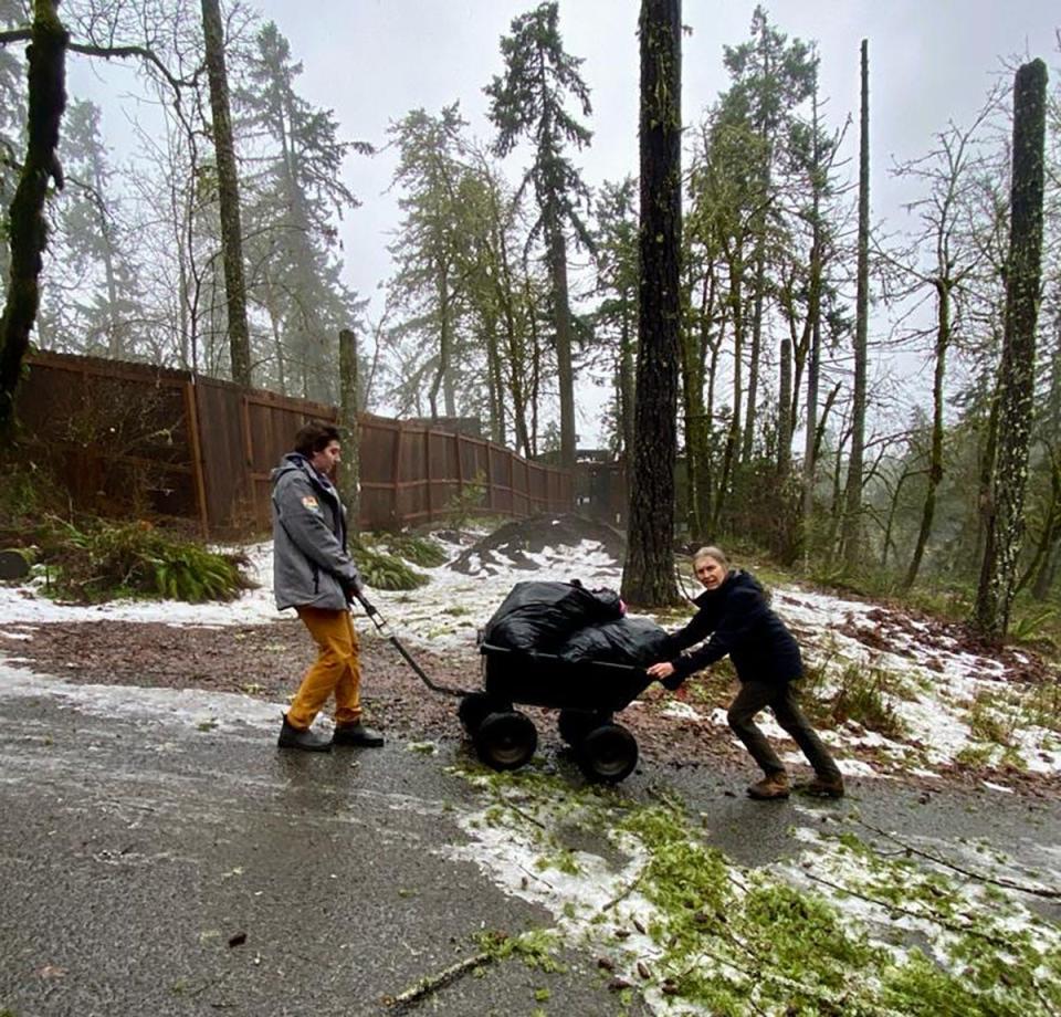 Cascades Raptor Center rehabilitation technician Ellie Hajduk, left, helps Ulrike Streicher, director of rehabilitation, with a wheelbarrow of debris as the staff digs out from the storm on Jan. 12.