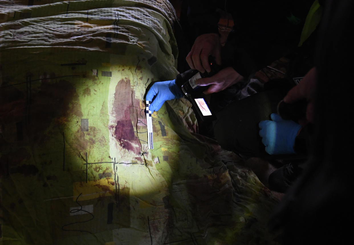 Blood-stained sheets are inspected in a home in Irpin, Ukraine, where the bodies of two men killed in an airstrike were found. 