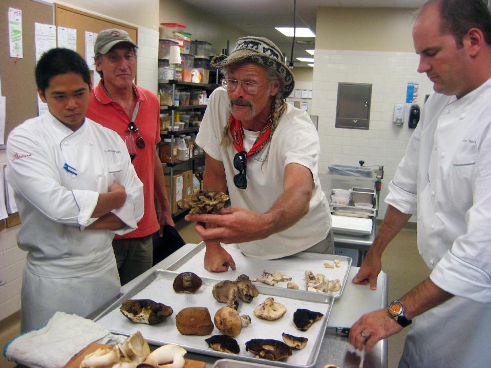 This Aug. 4, 2012 photo shows Four Seasons Resort Vail Executive Chef Jason Harrison, left, looking on as mushroom guide Larry Evans, center, shows off specimens collected during a foraging trip organized by Four Seasons Resort Vail in Vail, Colo. For $200 a person, the Four Seasons Resort Vail is sending out guided expeditions in luxury SUVs to look for mushrooms. The Mushrooms & Mercedes program includes a lunchtime break with wine, cheese and prosciutto, and ends with a three-course mushroom-themed meal back at the hotel.(AP Photo/Catherine Tsai)