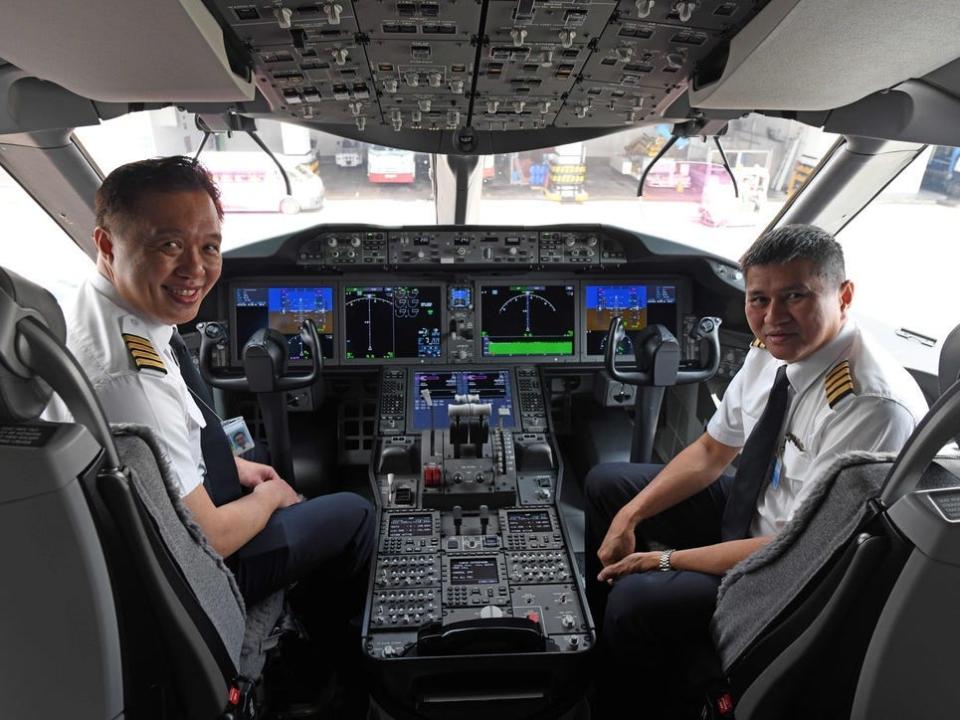 Captain Ian Cheng (L) and Captain Alan Chan Wai Fook (R) pose for a photograph in the cockpit of the Singapore Airlines (SIA) B787-10 after its arrival from Boeing's production facility in North Charleston, South Carolina at Singapore Changi Airport on March 28, 2018.