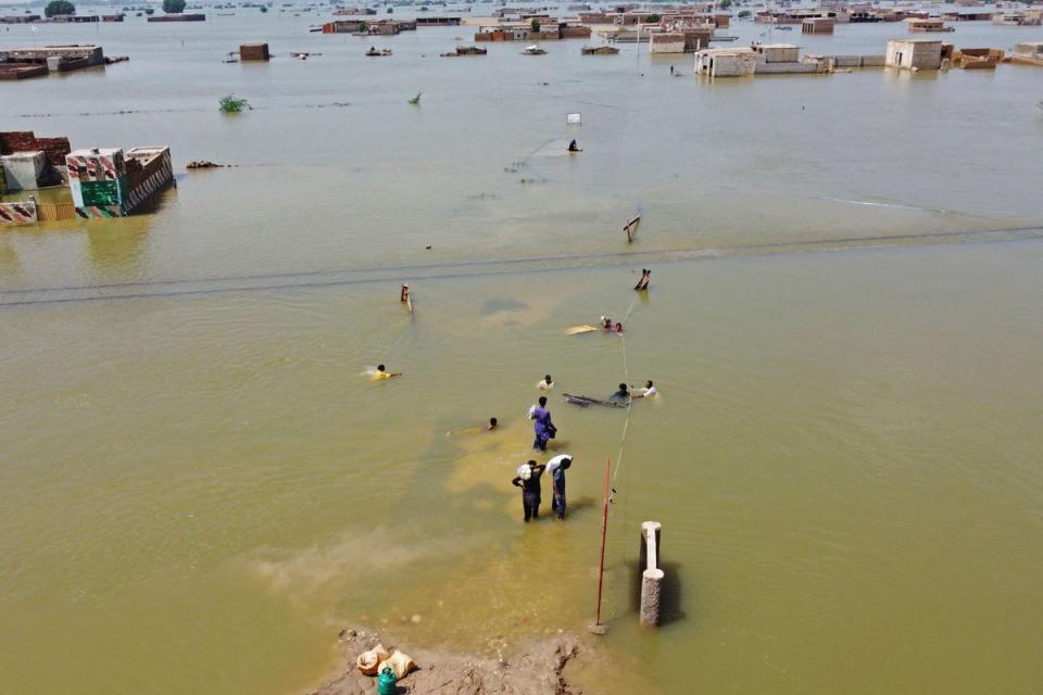 People wade through a submerged area of Balochistan province in Pakistan following the worst floods in the country’s history (AFP/Getty)