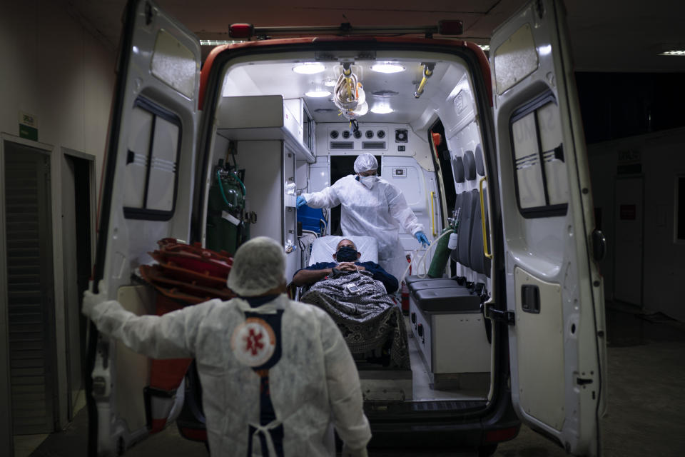 Mobile Emergency Care Service (SAMU) workers Gabrielle Carlos, top, and Joao Vericimo, move a COVID-19 patient to an ambulance as he is transferred to a municipal hospital dedicated to COVID-19 in Duque de Caxias, Rio de Janeiro state, Brazil, Tuesday, April 6, 2021. (AP Photo/Felipe Dana)