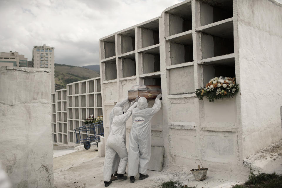 FILE - In this Sept. 24, 2020, file photo, cemetery workers place the coffin containing the remains of Jose de Arimateia, 65, who died from COVID-19 complications, into a niche at the municipal cemetery in Nova Iguacu, Brazil. The worldwide death toll from the coronavirus eclipsed 1 million, nine months into a crisis that has devastated the global economy, tested world leaders' resolve, pitted science against politics and forced multitudes to change the way they live, learn and work. (AP Photo/Silvia Izquierdo, File)