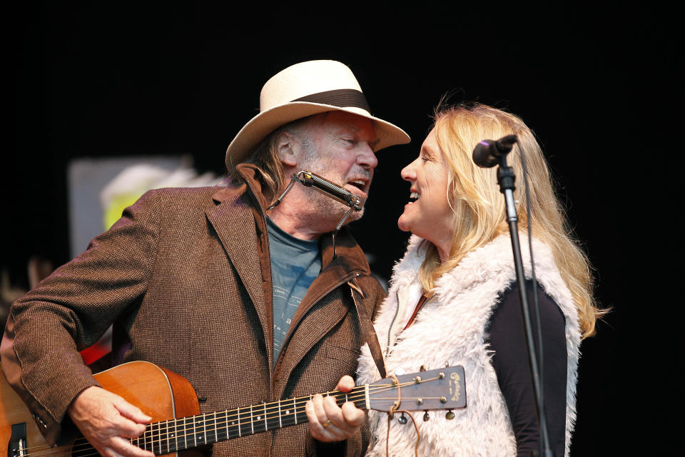 FILE - In this Oct. 24, 2010 file photo, Neil Young, left, and his wife Pegi Young perform during the Bridge School Benefit concert in Mountain View, Calif. Young, who with fellow musician and then-husband Neil Young helped found the Bridge School for children with speech and physical impairments, has died. Young died of cancer Tuesday, Jan. 1, 2019, in California, according to spokeswoman Michelle Gutenstein-Hinz. She was 66. (AP Photo/Tony Avelar, File)