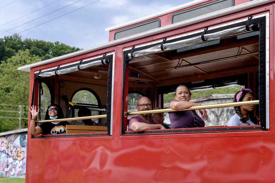 A woman waves from Asheville's sightseeing trolley as it travels on Old Lyman Street in the River Arts District June 10, 2021.