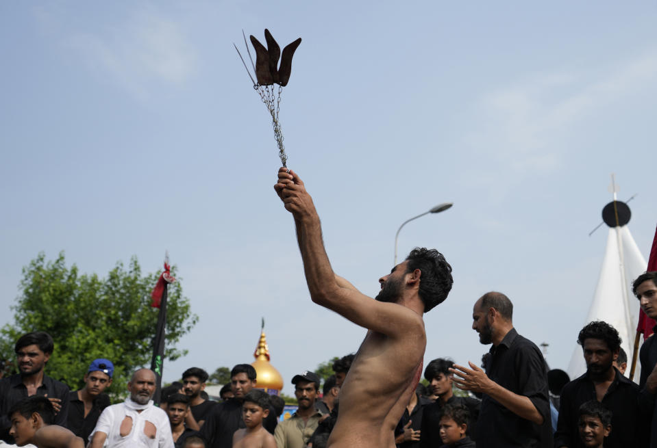 A Shiite Muslim flagellates himself with knifes on chains during a procession to mark Ashoura, in Islamabad, Pakistan, Friday, July 28, 2023. Ashoura is the Shiite Muslim commemoration marking the death of Hussein, the grandson of the Prophet Muhammad, at the Battle of Karbala in present-day Iraq in the 7th century. (AP Photo/Rahmat Gul)