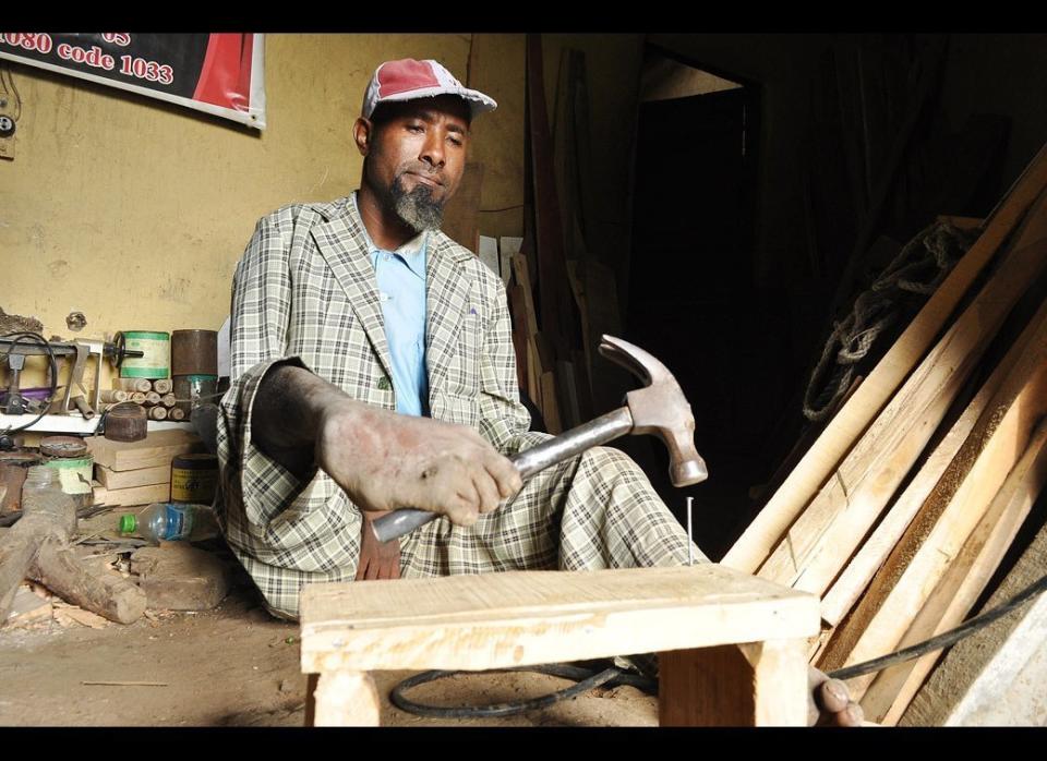 Carpenter Sintayehu Tishale, 42, hammers in a nail using his feet on July 9, 2011 in his workshop in Welete Suk, on the edge of Addis Ababa, Ethiopia.  