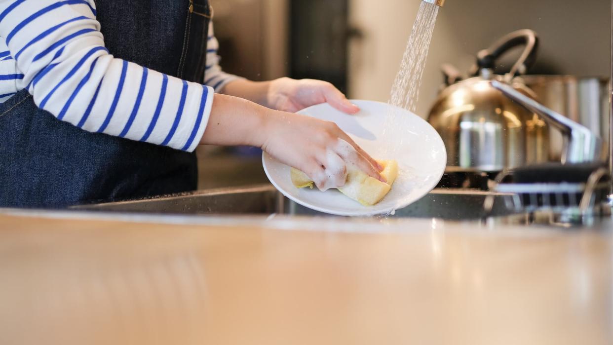 Waitress washing dish in the kitchen of restaurant.