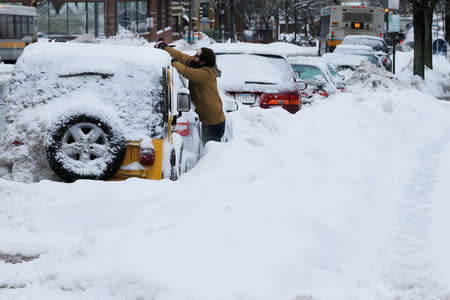 A man clears snow off his vehicle following a winter snow storm in Somerville, Massachusetts, U.S. February 13, 2017. REUTERS/Brian Snyder