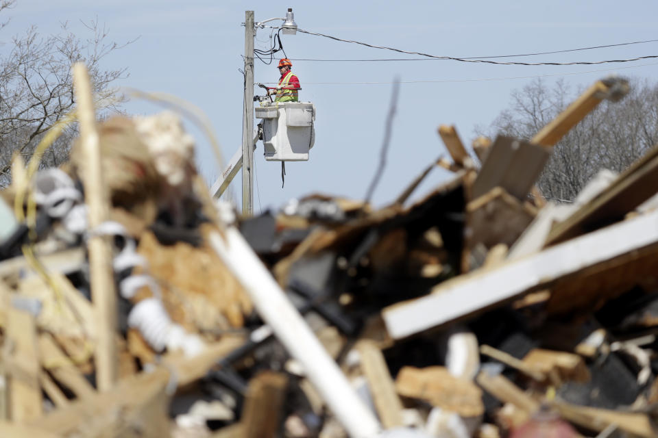 In this March 26, 2020, photo, a utility worker repairs a power line in Cookeville, Tenn. People still reeling from the deadly twisters that hit the state on March 3 now have to confront life in the age of coronavirus. (AP Photo/Mark Humphrey)