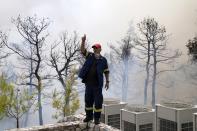 A firefighter instructs his colleagues during a wildfire in Ippokratios Politia village, about 35 kilometres (21 miles) north of Athens, Greece, Friday, Aug. 6, 2021. Thousands of people fled wildfires burning out of control in Greece and Turkey on Friday, as a protracted heat wave turned forests into tinderboxes and flames threatened populated areas, electricity installations and historic sites. (AP Photo/Thanassis Stavrakis)