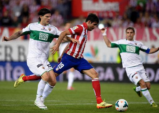 El defensor del Elche Sergio Pelegrín (i) intenta frenar al delantero del Atlético Diego Costa en el partido de Liga jugado el 18 de abril de 2014 en Madrid (AFP | Dani Pozo)