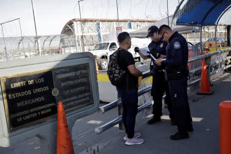 U.S. Customs and Border Protection officers inspect documents from a Central American migrant seeking asylum at Paso del Norte International border bridge, in this picture taken from Ciudad Juarez