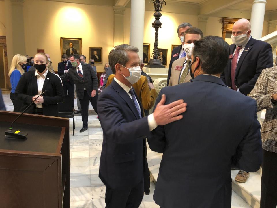 Georgia Gov. Brian Kemp speaks to Lt. Gov Geoff Duncan on Tuesday, Feb. 2, 2021, after a news conference in Atlanta where Kemp proposed letting some retired teachers return to work at full pay. Kemp also wants to do more to recruit teachers from the military and historically Black colleges. (AP Photo/Jeff Amy)