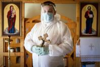 In this photo taken on Thursday, May 28, 2020, Ukrainian Greek Catholic Church priest, Father Yaroslav Rokhman wearing protective gear to protect against coronavirus, poses for a photo at a hospice in Ivano-Frankivsk, Ukraine. Rokhman, a priest in the Ukrainian Greek Catholic Church, is pleased to be able to return to performing one of a cleric's most heartfelt duties. As the coronavirus pandemic's grip on Ukraine slowly recedes, priests received permission on May 22 to again hold services and visit the sick. (AP Photo/Evgeniy Maloletka)