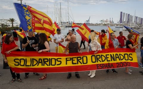 Far-right wing protesters hold Spanish flags and a banner reading 'Solidarity but in order' as they demonstrate against the arrival of migrants in the Aquarius ship at the port of Valencia - Credit: Getty