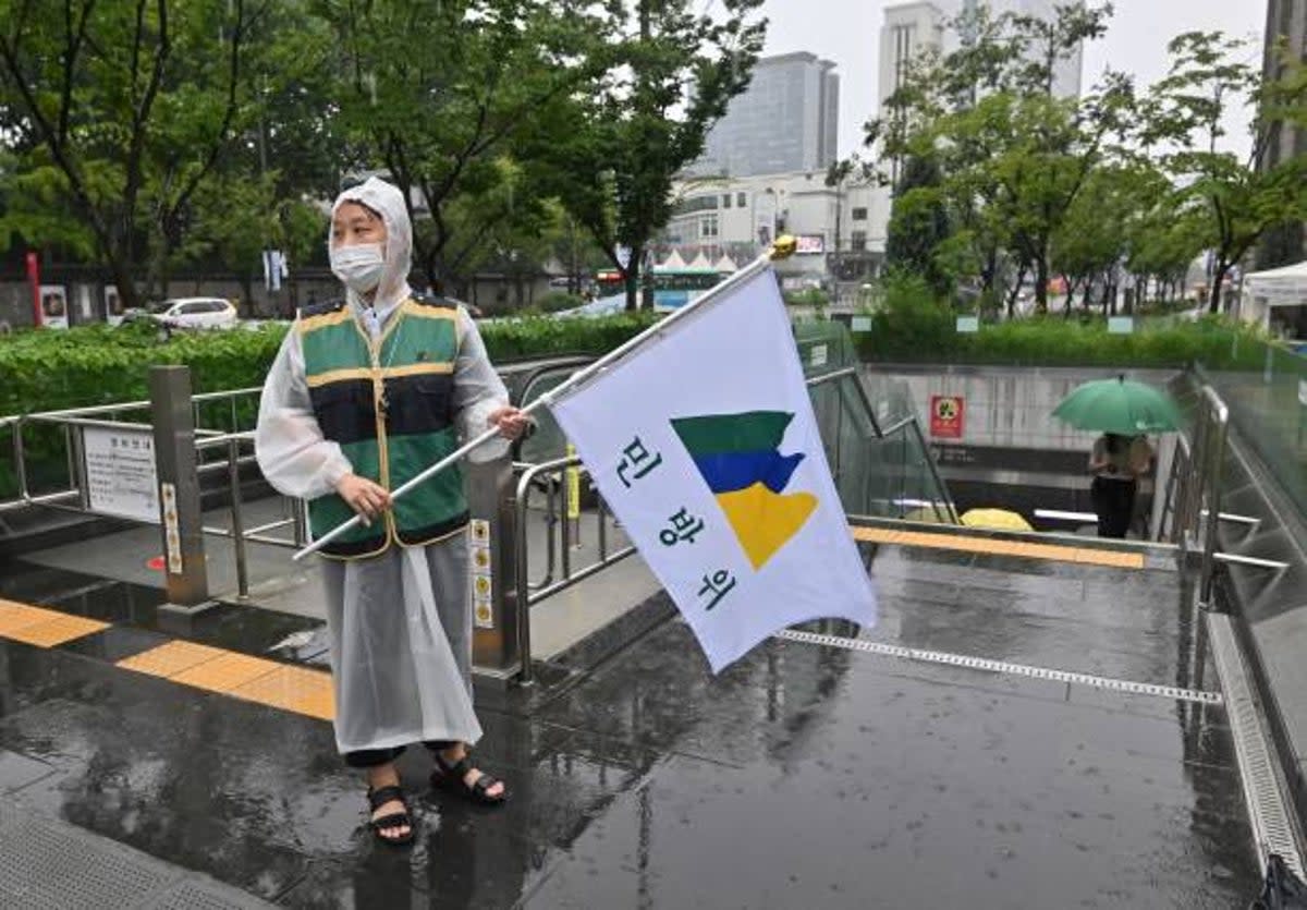 A South Korean government official holding a civil defence flag guides citizens into underground facilities after an air raid siren sounded during a civil defence drill against possible artillery attacks by North Korea in Seoul on 23 August 2023 (AFP via Getty Images)