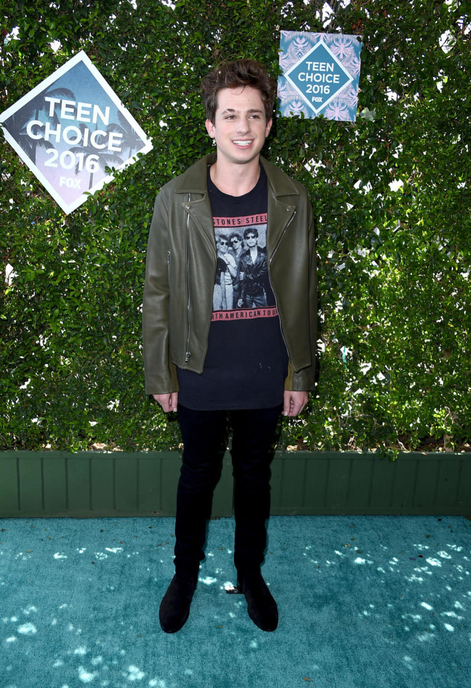 Charlie Puth wearing a green leather jacket and Rolling Stones T-shirt 