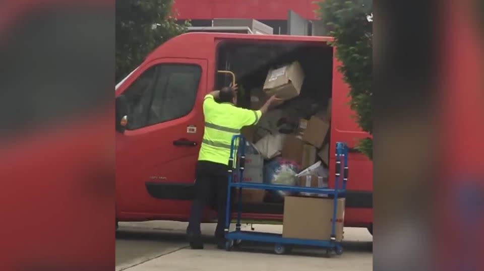 The worker was seen lobbing package after package from a tray into the van just outside Arena post office in Melbourne. Source: Facebook / Glenn Burr