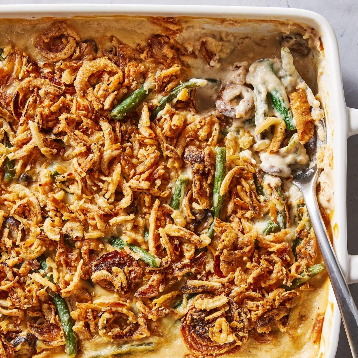 green bean casserole in a white baking dish with crunchy onions on top