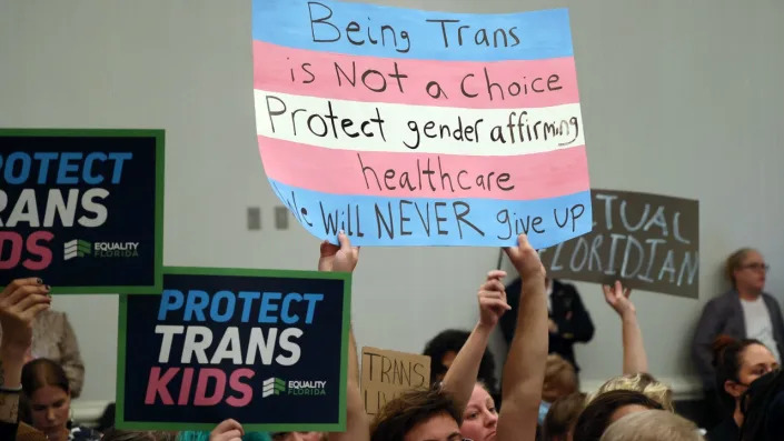 People hold signs supporting the right of children to obtain transgender medical care