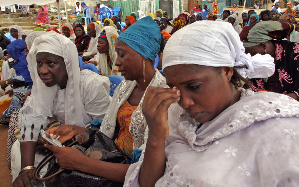 In this photo taken on Wednesday, April 2, 2014, Sira Kone Fadiga, right, the aunt of Ivorian fashion model Awa Fadiga, cries at her funeral with unidentified family members in Abidjan, Ivory Coast. Awa Fadiga was attacked at night in a taxi that was taking her home to an upscale neighborhood in Ivory Coast’s capital. Two witnesses say they saw the locally famous fashion model being thrown out of the cab under a bridge, apparently unconscious. Firefighters rushed the 23-year-old to the Central University Hospital where she was left untreated for more than 12 hours and slipped into a coma _ all because there was no one immediately available to pay her medical fees, her family said. (AP Photo/Sevi Herve Gbekide )
