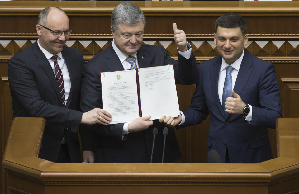 Ukrainian President Petro Poroshenko, center, Prime Minister Volodymyr Groysman, right, and parliament speaker Andriy Parubiy show the newly signed Constitutional amendment to joining the EU and NATO in Ukrainian parliament in Kiev, Ukraine, Tuesday, Feb. 19, 2019. (Mikhail Palinchak, Presidential Press Service Pool Photo via AP)