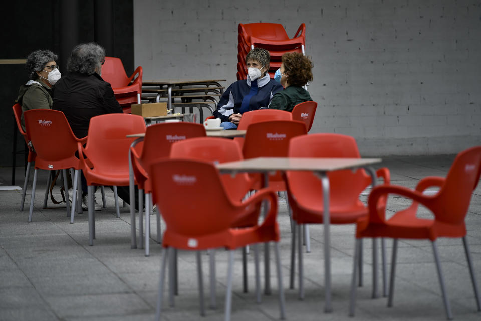 People sit in a bar terrace while wearing face mask protection against the coronavirus, in Pamplona, northern Spain, Thursday, May 14, 2020. Roughly half of 47 million Spaniards are stepping into a softer version of the country's coronavirus strict confinement and are beginning to socialize, shop in small establishments and enjoy a meal or a coffee in restaurants and bars with outdoor seating. The hard-hit region around the Spanish capital, Madrid, and the economic powerhouse of Barcelona, in the northeastern Catalonia region, are among those territories that remain under stricter measures. (AP Photo/Alvaro Barrientos)